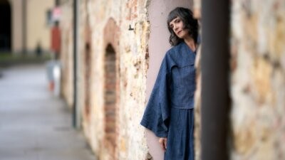 Cristina Donà appoggiata a un muro di pietra nella foto promozionale dell'album L'arte di scomparire