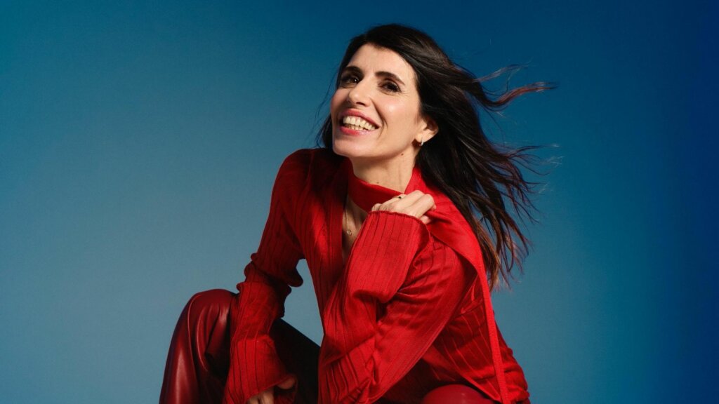 Giorgia sorride con un maglione rosso su sfondo blu