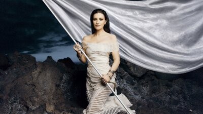 Laura Pausini con una bandiera bianca sulle rocce, nell'immagine ufficiale del tour per il concerto all'Unipol Dome di Milano del 2 dicembre 2027