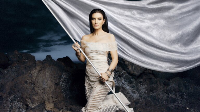 Laura Pausini con una bandiera bianca sulle rocce, nell'immagine ufficiale del tour per il concerto all'Unipol Dome di Milano del 2 dicembre 2027