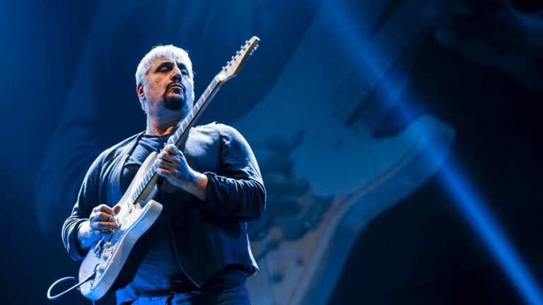 Pino Daniele sul palco suona la chitarra elettrica con una luce blu alle spalle