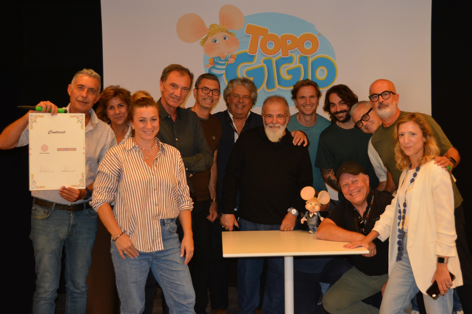 Il team di Sony Music Italy posa con Topo Gigio e il contratto davanti al logo del personaggio