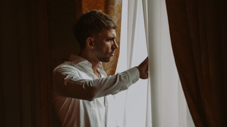 Vegas Jones affacciato a una finestra tra le tende, foto promozionale del singolo Nel dubbio