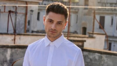 Virginio in camicia bianca su una terrazza, nella foto promozionale del singolo Dio nella pioggia
